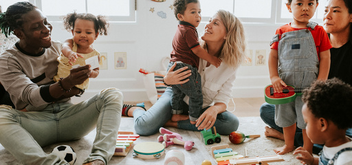 Toddlers playing musical instruments with parents in kindergarten