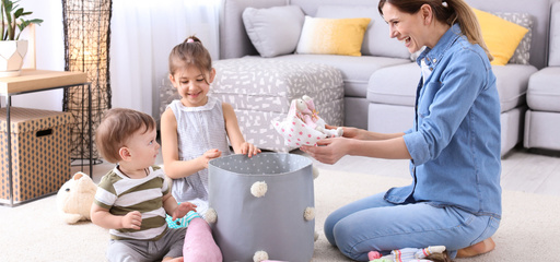 Mother toddlers picking up toys putting in box